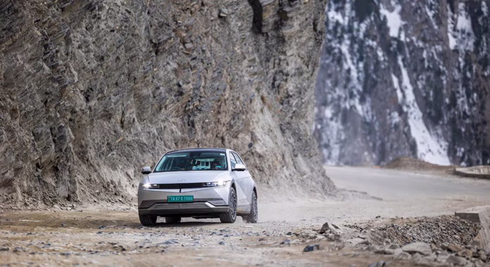 ioniq_5_estrada_recorde_guinness.avif IONIQ 5 na cor prata passando em uma estrada ao lado de uma montanha durante o dia.