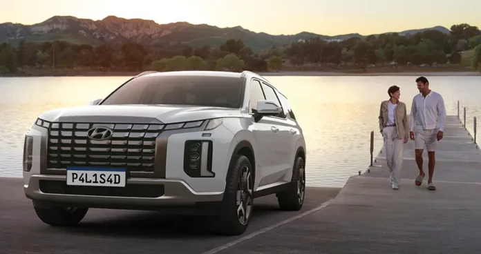 palisade_motor_em_v_paisagem.webp.webp PALISADE ambientado em ponte com lago e montanhas ao fundo no pôr do sol, com casal sobre a ponte caminhando juntos.