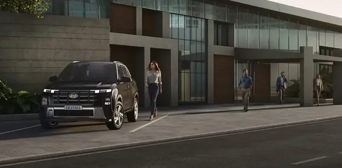 creta_comfort_rua.webp.webp Modelo CRETA Comfort na cor preta estacionado na rua durante o dia com mulher caminhando ao lado.