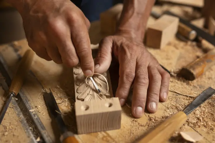 Mãos esculpindo a madeira.